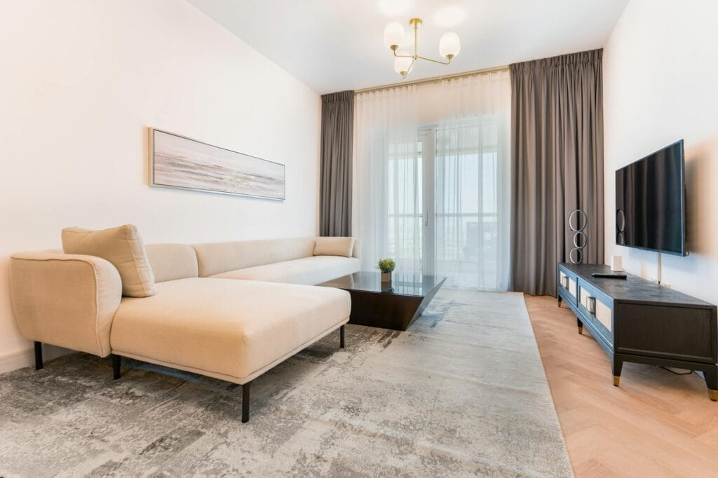 Minimalist living room with beige sectional sofa, neutral walls and warm wood floor