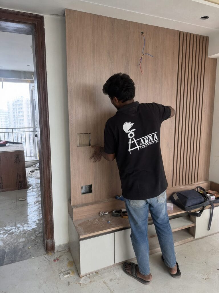 Wooden feature wall and TV unit paneling by Aarna Constructions in Greater Noida