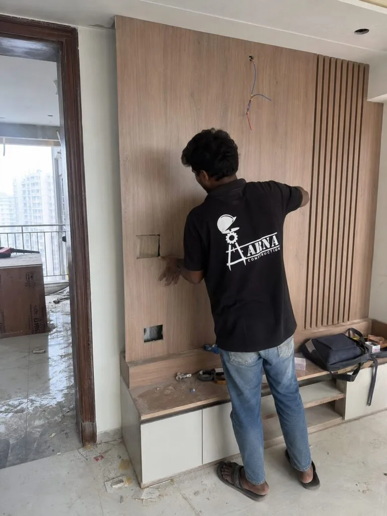 Wooden feature wall and TV unit paneling by Aarna Constructions in Greater Noida
