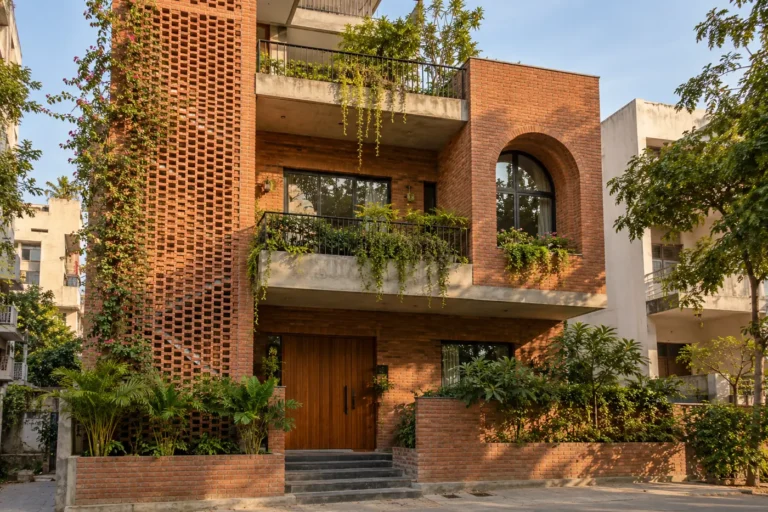 Exposed red brick house front elevation with brick jaali screen and arched niche
