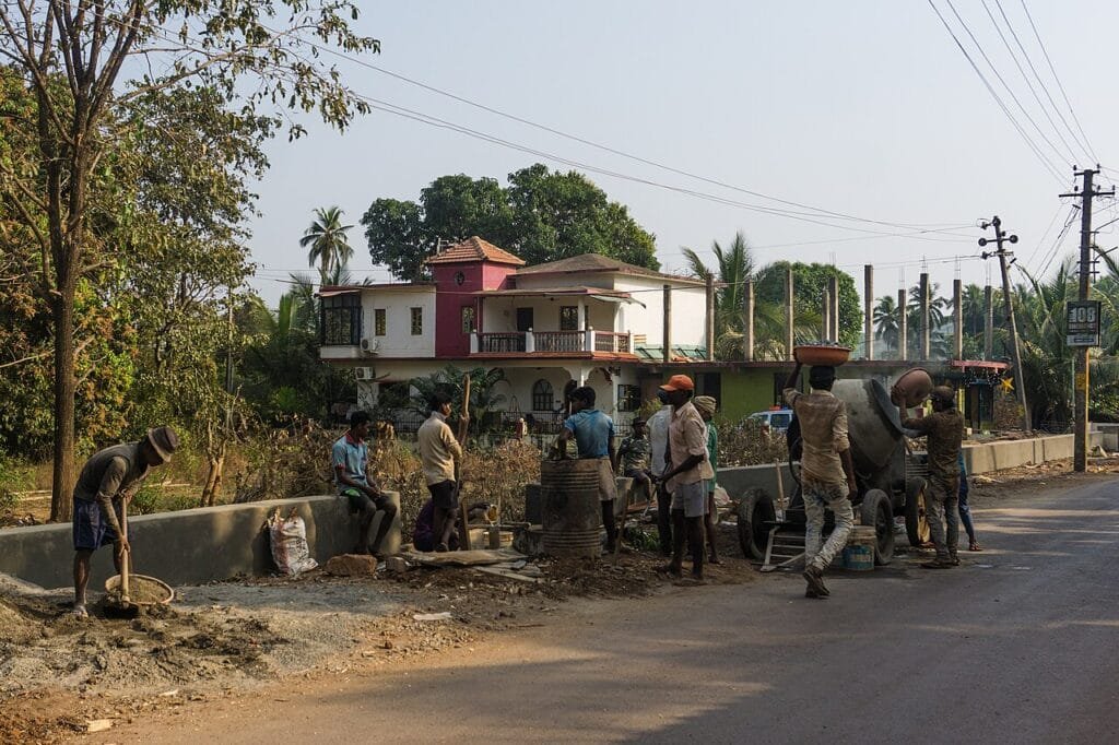 Construction workers with a concrete mixer at a building site in India