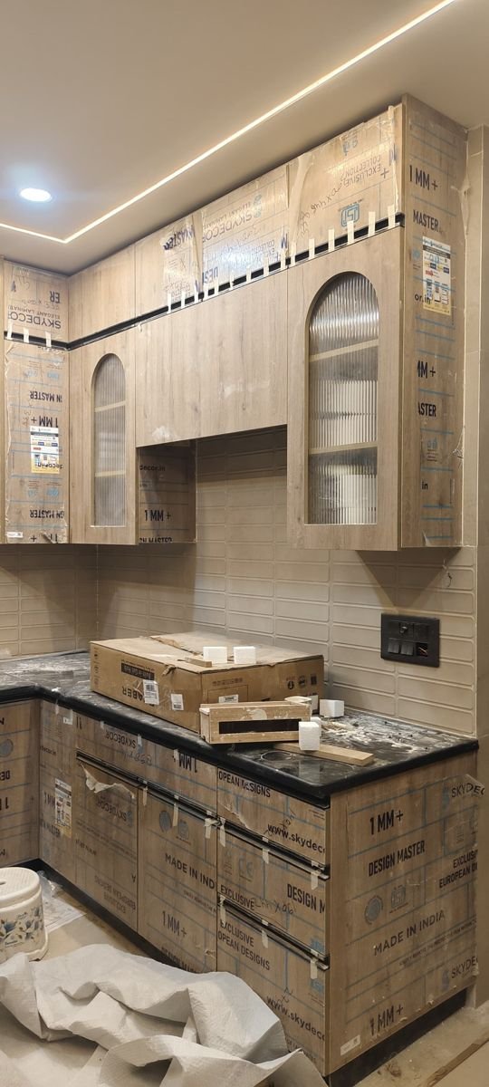 Modular kitchen in a wood-grain laminate finish, taking shape at a home in Greater Noida