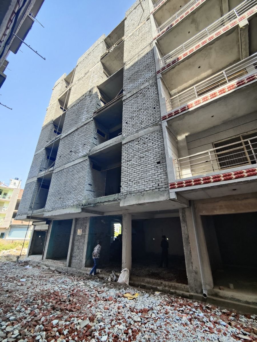 Multi-storey building under construction in Greater Noida, with grey brick infill between the concrete floor slabs and s